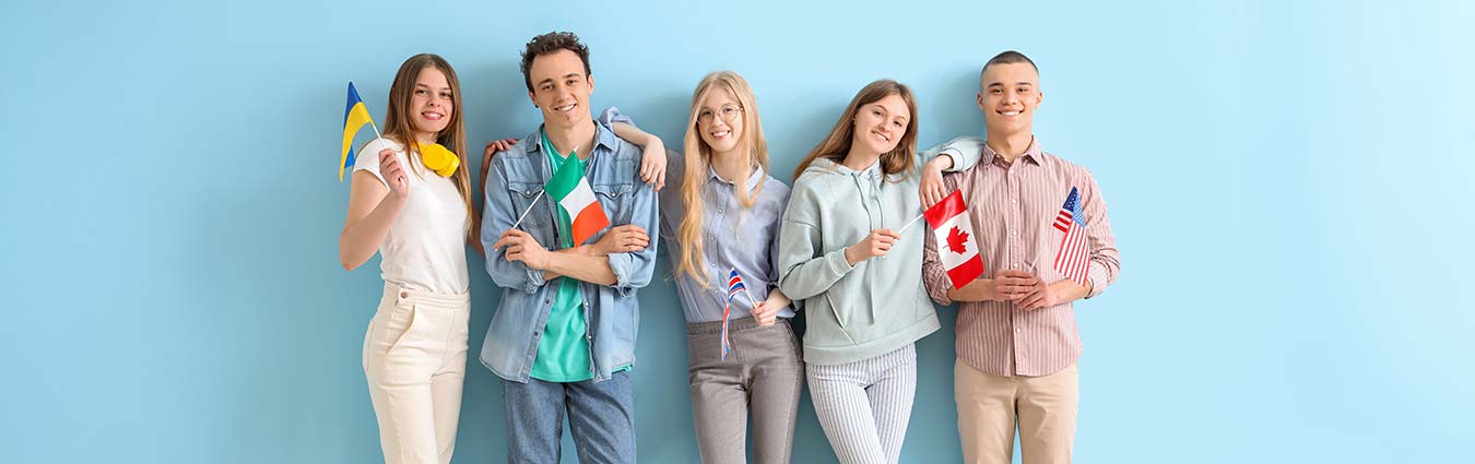 Group of students with flags of different countries near blue wall